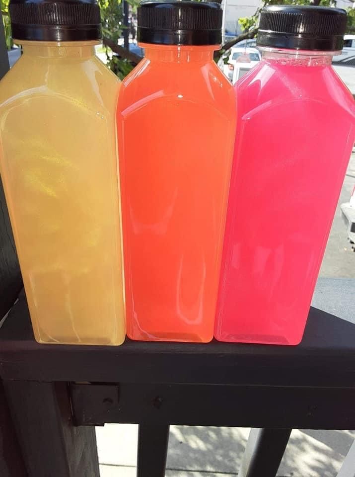 Garrafas altas com bebidas amarelas, laranja e rosa